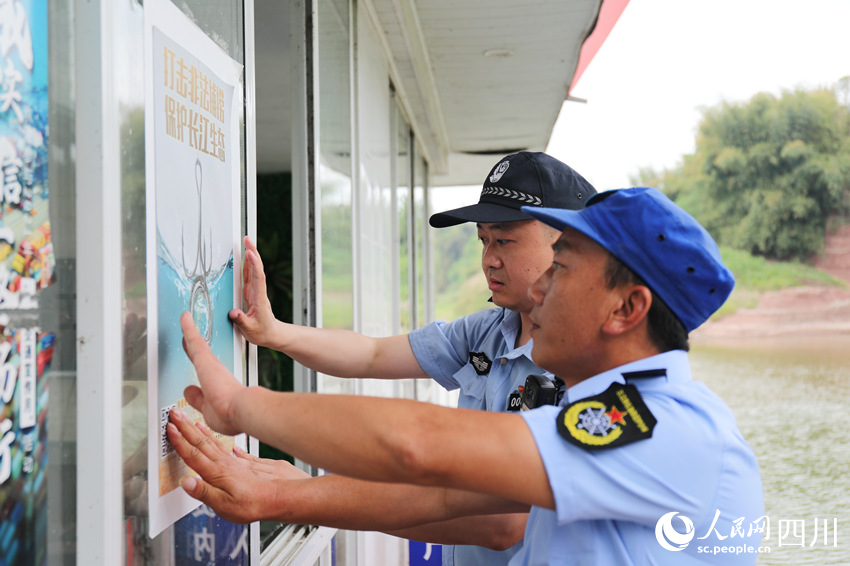 長江航運(yùn)公安民警與漁政協(xié)助巡護(hù)隊(duì)員一同張貼“禁捕”宣傳海報(bào)。人民網(wǎng) 趙祖樂攝