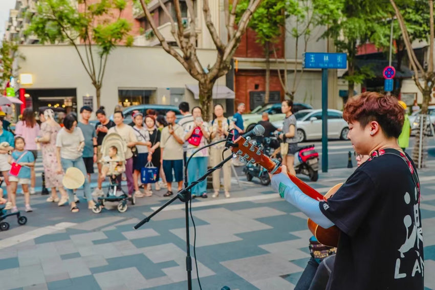 街頭藝人的表演深深吸引路人。玉林街道辦事處供圖